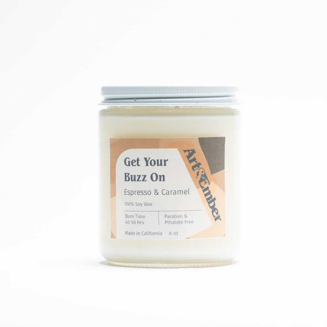 Candle jar labeled 'Get Your Buzz On' by Artisanal on a white background