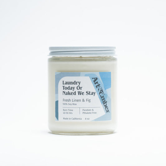 Candle jar labeled 'Naked We Stay' on a white background